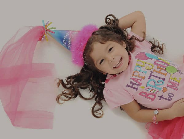 Young girl wearing a birthday hat and top